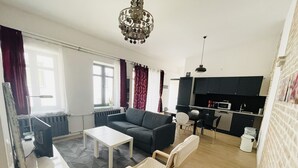A modern living room with a sofa, coffee table, and a dining area with a table and chairs.