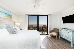 A hotel room with a large bed, a television, a dresser, and a balcony with a view. - Oceanfront, Newly Renovated, Luxury Two-Story Penthouse - Shipwatch 418 (Isle of Palms)