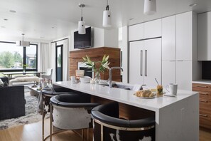 Una cucina moderna con isola centrale, sgabelli da bar, una TV a schermo piatto e un'ampia finestra con vista sull'esterno.