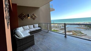 Un balcon avec un canapé en osier et vue sur la plage.