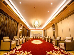A hotel conference room with a red carpet, rows of chairs, a chandelier, and a cityscape mural. - Fuyue Hotel (Shanghai)