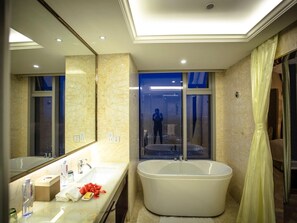 A modern bathroom with a freestanding bathtub, a large mirror, and a window with a view of the city at night. - Fuyue Hotel (Shanghai)