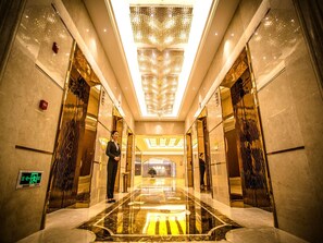 A hotel lobby with a reflective marble floor, a large chandelier, and mirrored walls. - Fuyue Hotel (Shanghai)