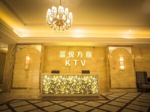A lobby with a chandelier, a reception desk, and a patterned wall. - Fuyue Hotel (Shanghai)