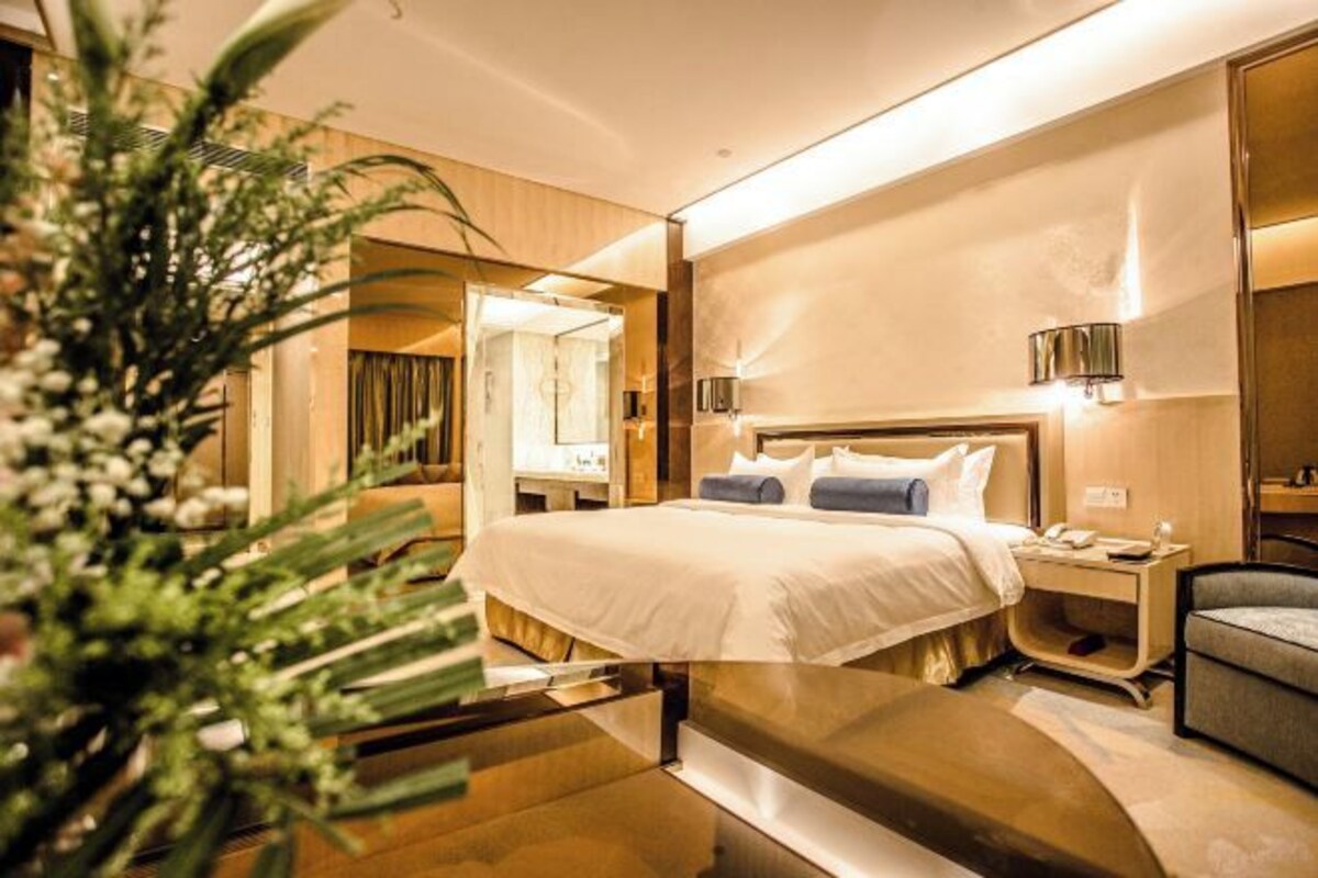 Une chambre d’hôtel moderne avec un grand lit, des tables de chevet, une chaise et un miroir.