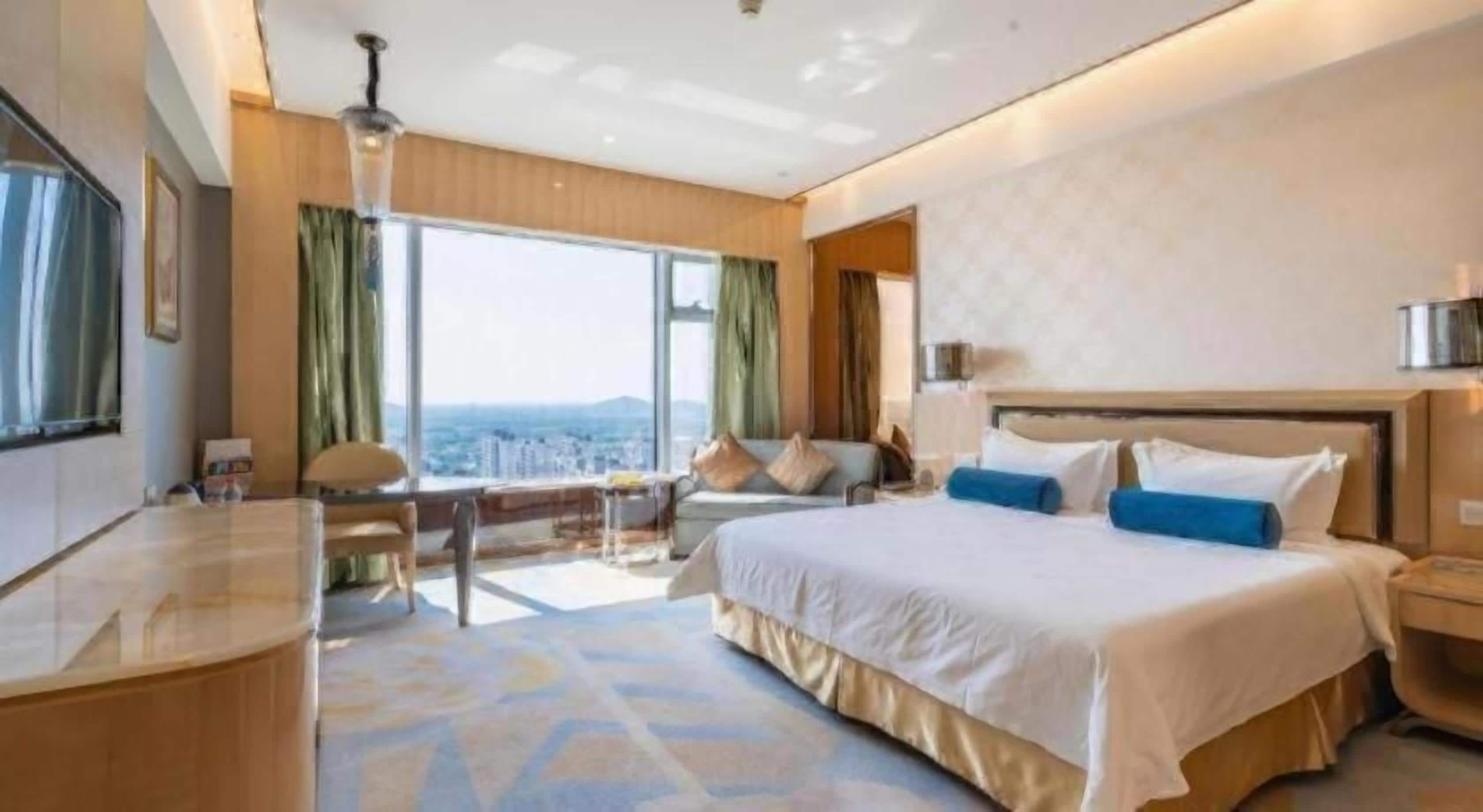 A hotel room with a large bed, a desk, and a view of the city.