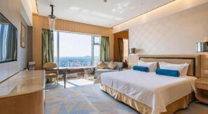 Une chambre d’hôtel avec un grand lit, un bureau et une vue sur la ville.