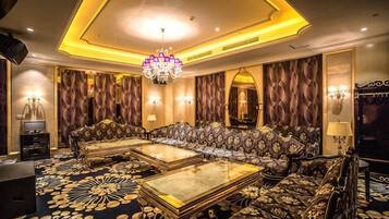 A luxurious room with a sofa set, two coffee tables, a chandelier, and a patterned carpet.