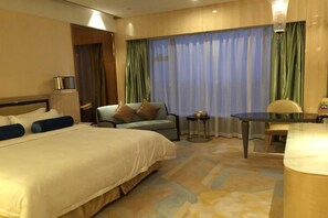 A hotel room with a large bed, a desk, a chair, and a small table. - Fuyue Hotel (Shanghai)