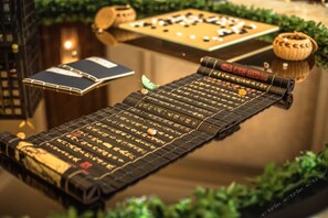A traditional Chinese chessboard with pieces, a book, and a decorative item on a reflective surface. - Fuyue Hotel (Shanghai)