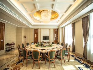 Une salle à manger élégante, avec une table ronde, des chaises, un lustre et une grande fenêtre.