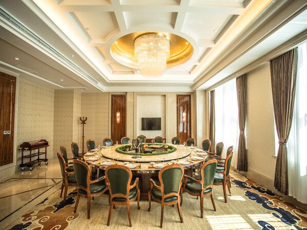 A formal dining room with a round table, chairs, a chandelier, and a large window. - Fuyue Hotel (Shanghai)