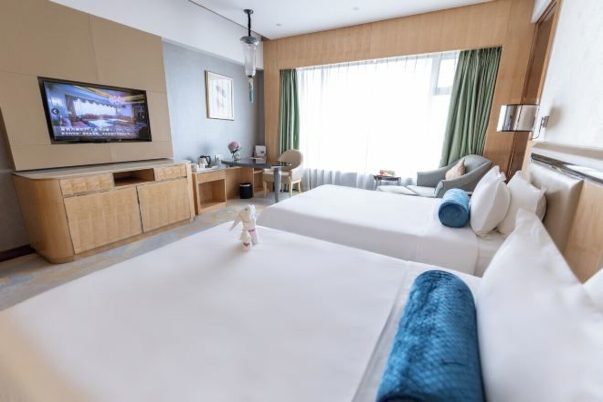 Une chambre d’hôtel avec deux lits, une télévision, un bureau et une chaise.