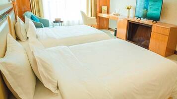 A hotel room with two beds, a desk, a chair, and a television.