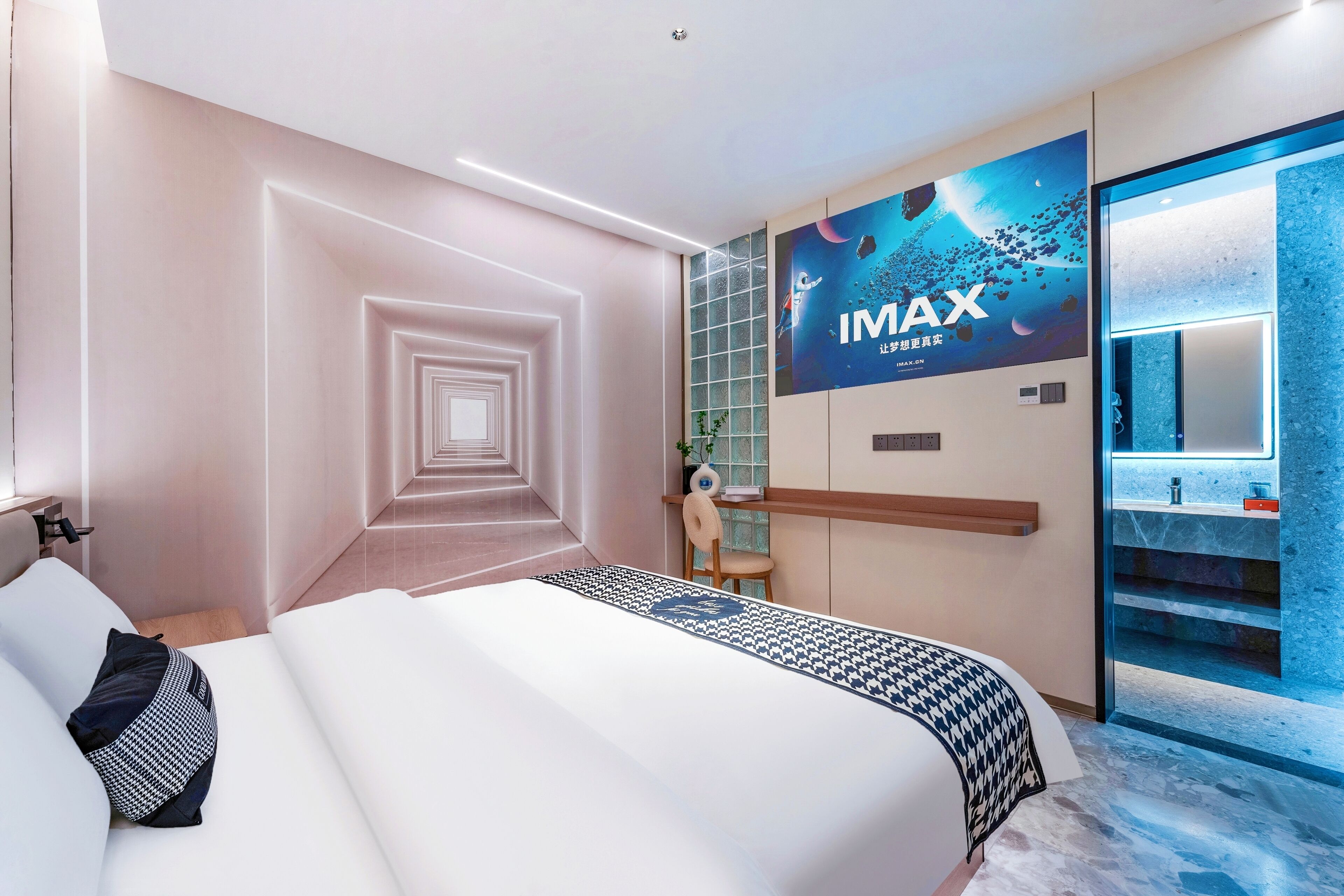Una habitación de hotel moderna con una cama grande, un televisor montado en la pared y un baño con encimera de mármol.