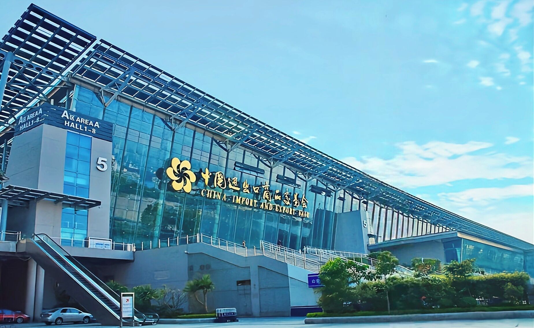 Ein modernes Gebäude mit einer großen Glasfassade, einem gut sichtbaren Schild mit der Aufschrift "China Import and Export Fair" und einer Treppe zum Eingang.