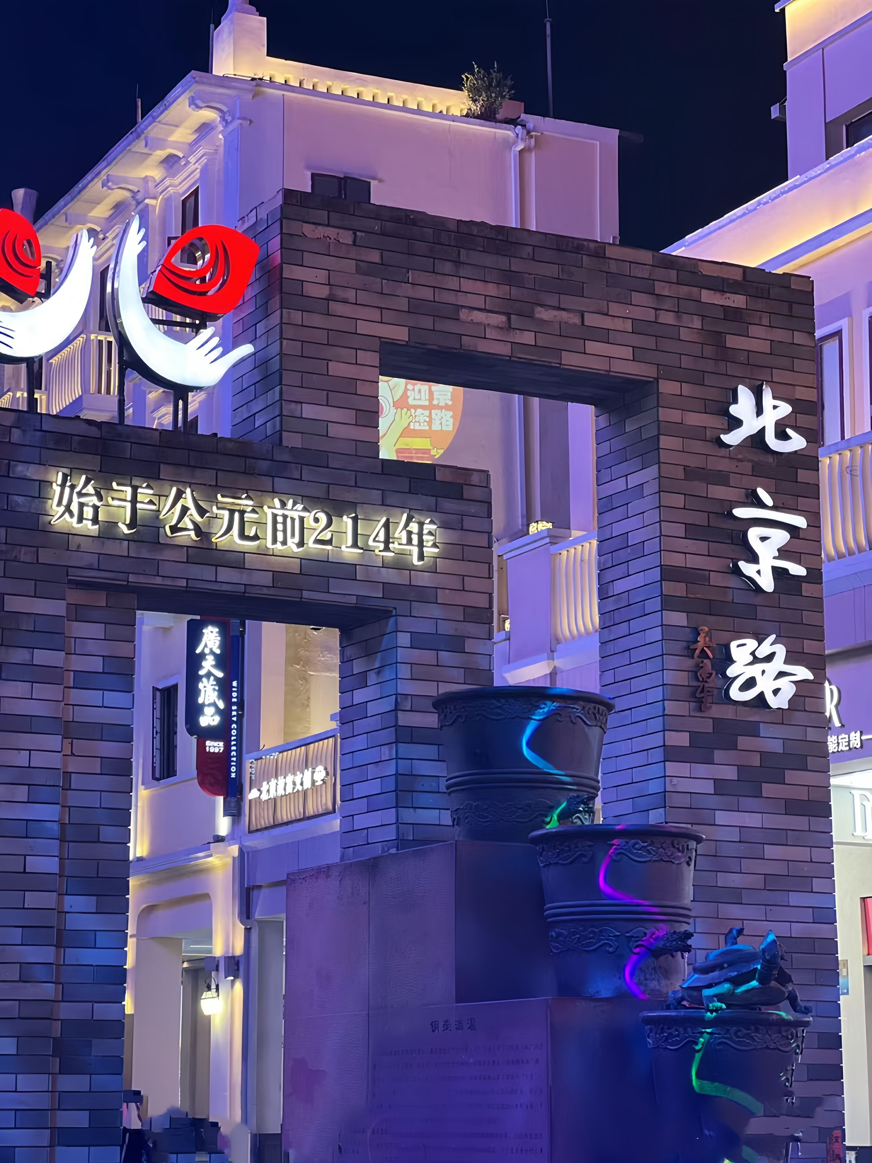A building with illuminated signs and a traditional Chinese-style water feature.