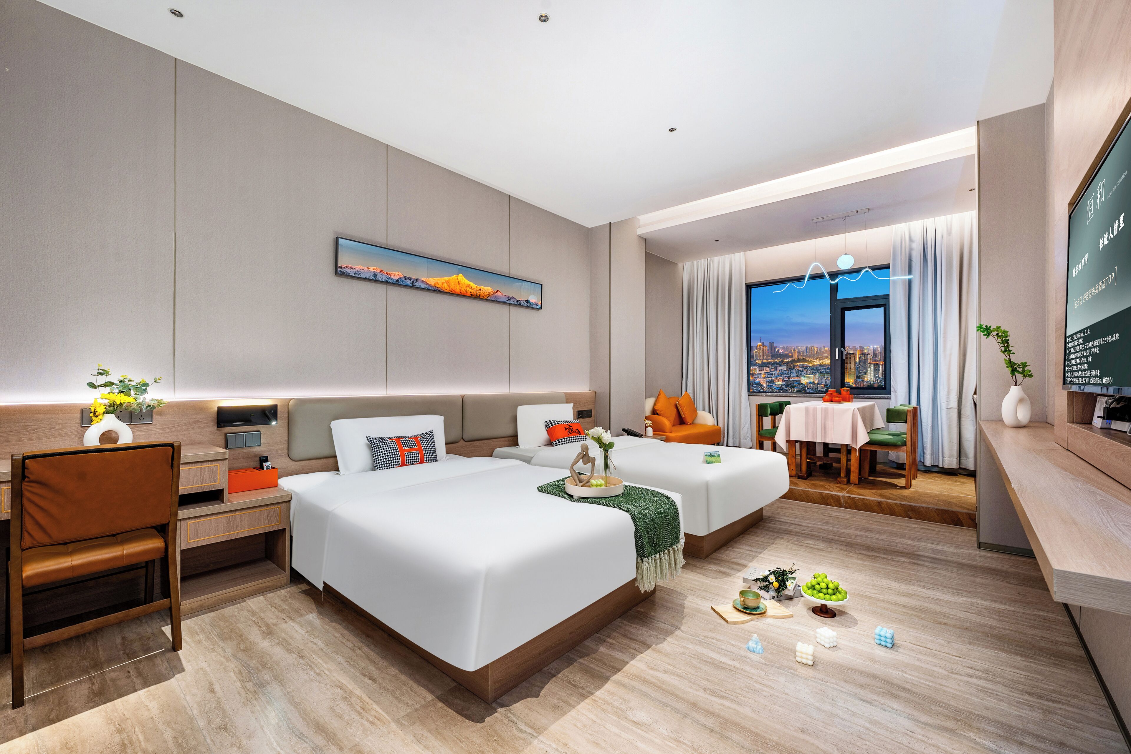 A modern hotel room with two beds, a desk, a dining area with a table and chairs, and a large window offering a city view.