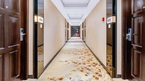 Ein Hotelgang mit Holztüren, nummerierten Zimmern und einem Teppich mit einem Blumenmuster.