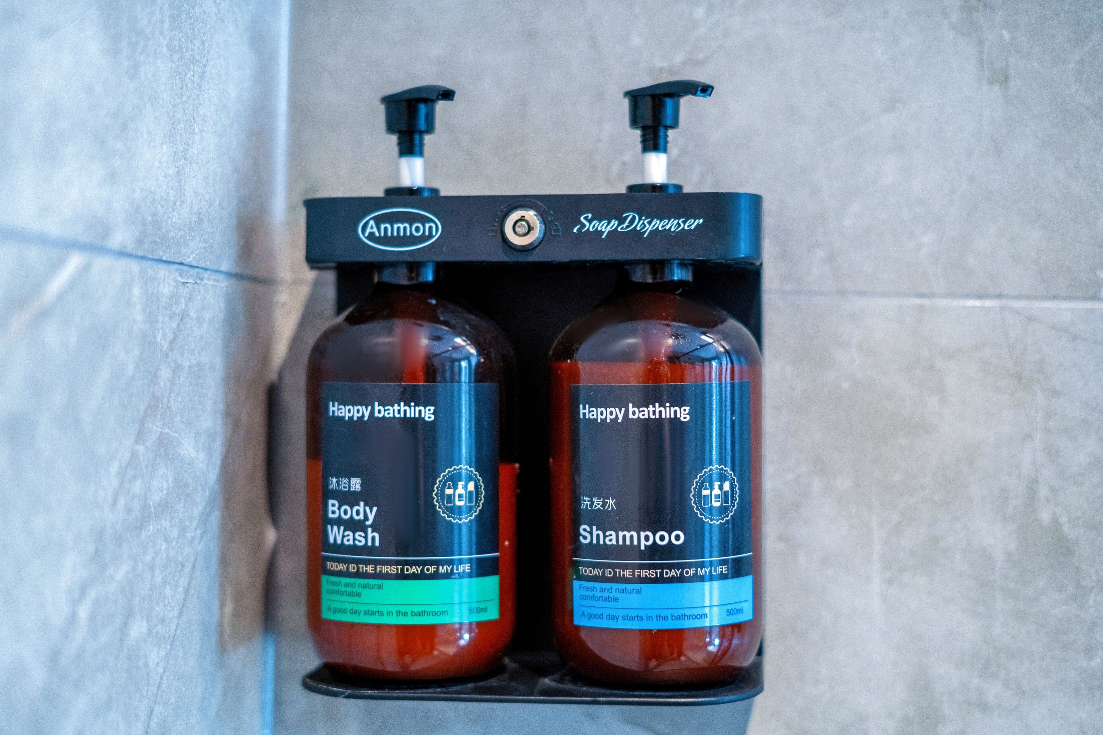 A soap dispenser with two bottles of Annon body wash and shampoo.