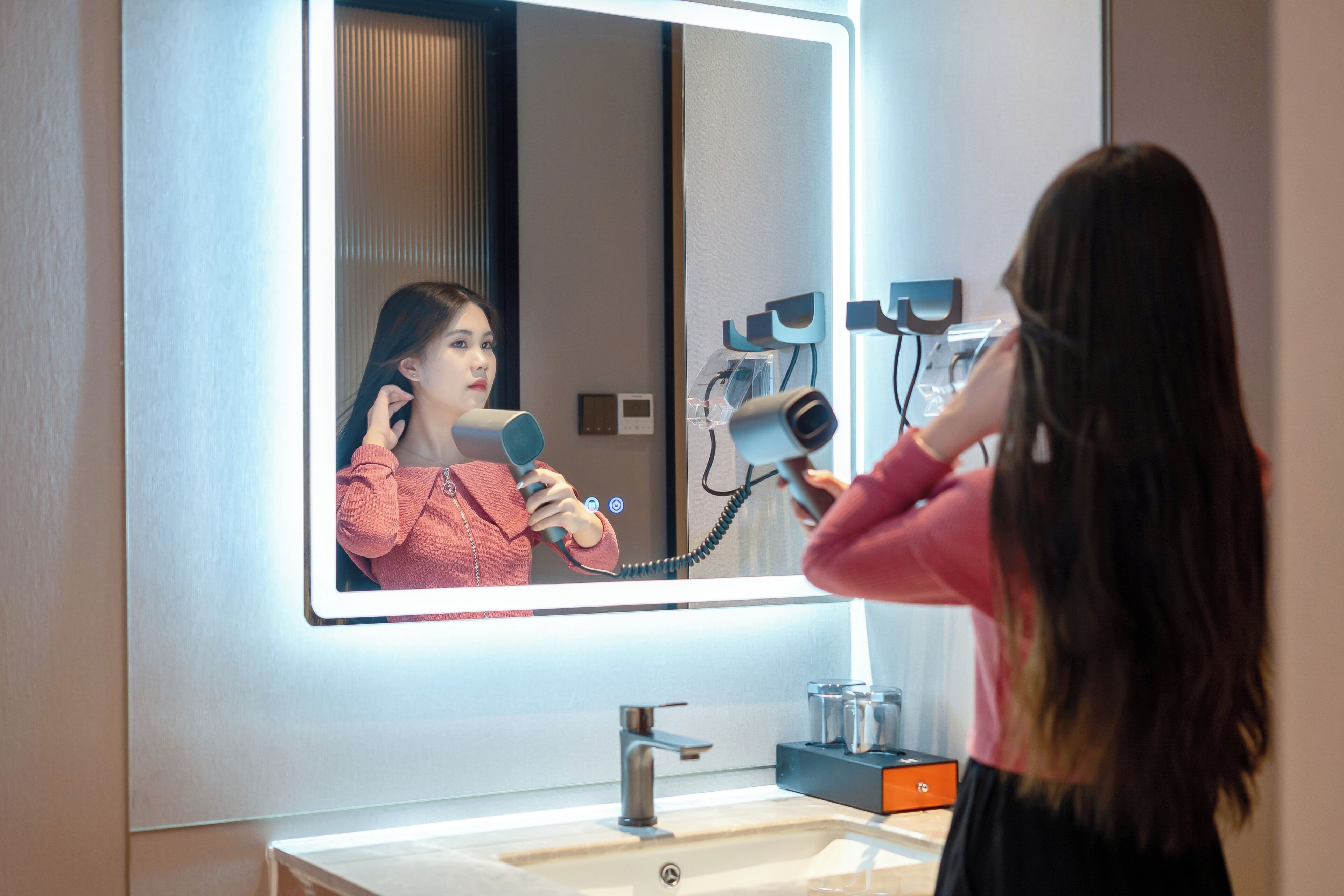 A bathroom with a large mirror, a sink, and a hairdryer.