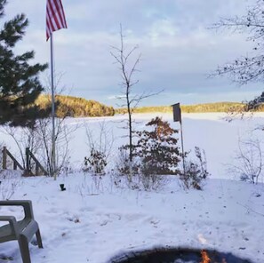 A snowy landscape with a flag, a bench, and a small flagpole.