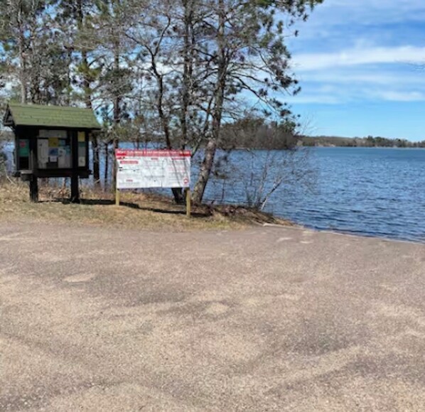 A lakeside picnic area with a shelter and informational sign.