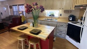 A compact kitchen with a central island, wooden cabinets, and a modern stove. - Three Mile Lake -WATERFRONT and completely Furnished lake house . (Port Barre)