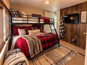 A bunk bed room with a television, a wall-mounted cross, and a 'Good Night Darlin'' sign.