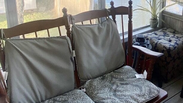 A wooden bench with patterned cushions in a covered porch with large windows overlooking a body of water and trees. - Three Mile Lake -WATERFRONT and completely Furnished lake house . (Port Barre)