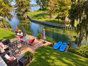 Terraza con mobiliario exterior, kayaks y vista a un cuerpo de agua.