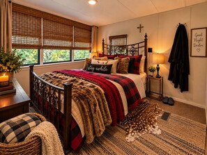 A cozy bedroom with a bed, a nightstand, a lamp, a cross on the wall, and a framed sign. -   Peaceful Waterfront Retreat on Three Mile Lake • Bring Your Boat (Port Barre)