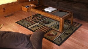 L’intérieur d’un chalet accueillant, avec un plancher en bois, un canapé marron, une table basse en verre et un tapis à motifs.