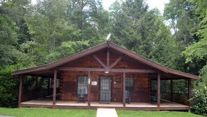 Une cabane en bois rustique, dotée d’un porche, d’une porte et d’une fenêtre.