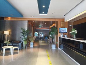 A modern hotel lobby with a reception desk, seating area, and potted plants. - Jinjiang Inn (Wuhan)