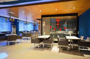 A modern restaurant interior with tables and chairs, a decorative wall with red ornaments, and a ceiling with recessed lighting. - Jinjiang Inn (Wuhan)
