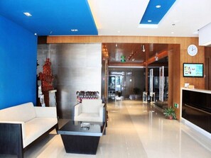 A modern lobby with a reception desk, a seating area with a sofa and a coffee table, and a decorative sculpture. - Jinjiang Inn (Wuhan)