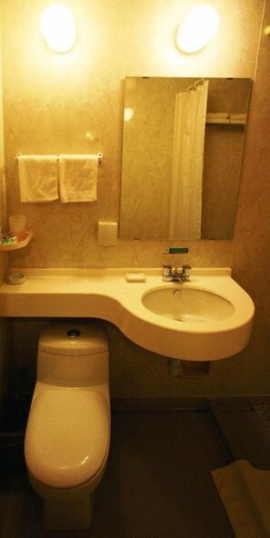 A bathroom with a white toilet, a sink, and a mirror. - Jinjiang Inn (Wuhan)