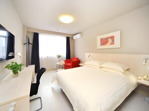 A hotel room with a bed, bedside table, lamp, desk, chair, and a window with curtains. - Jinjiang Inn (Wuhan)