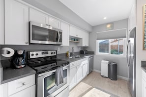 A modern kitchen with stainless steel appliances, white cabinetry, and a window providing natural light.
