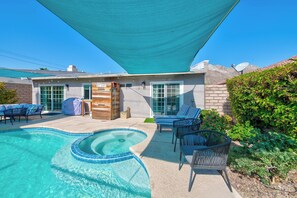 A swimming pool with a built-in jacuzzi, surrounded by outdoor furniture and a covered patio area.