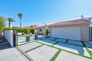 Ein Wohnhaus mit Garage, einer gepflasterten Auffahrt und Grasränder sowie einer Palme.