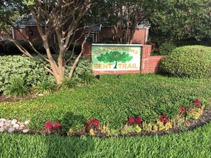 Welcome to the Condominiums of Bent Trail, surrounded by a beautifully maintained garden with a variety of flowering plants and shrubs.