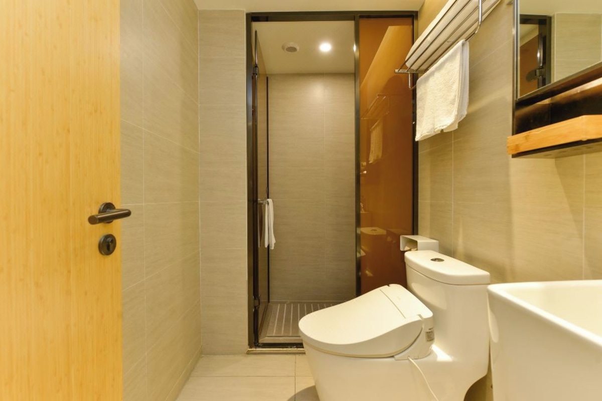 A bathroom with a toilet, shower, and a wooden door.