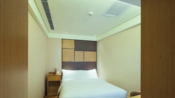 A hotel room with a bed, bedside table, and a desk. - Ji Hotel (Shanghai)