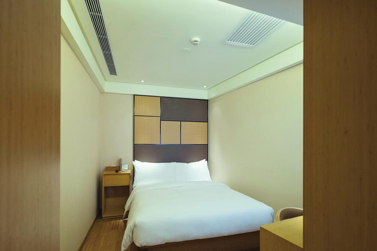 Une chambre d’hôtel avec un lit, une table de chevet et un bureau.