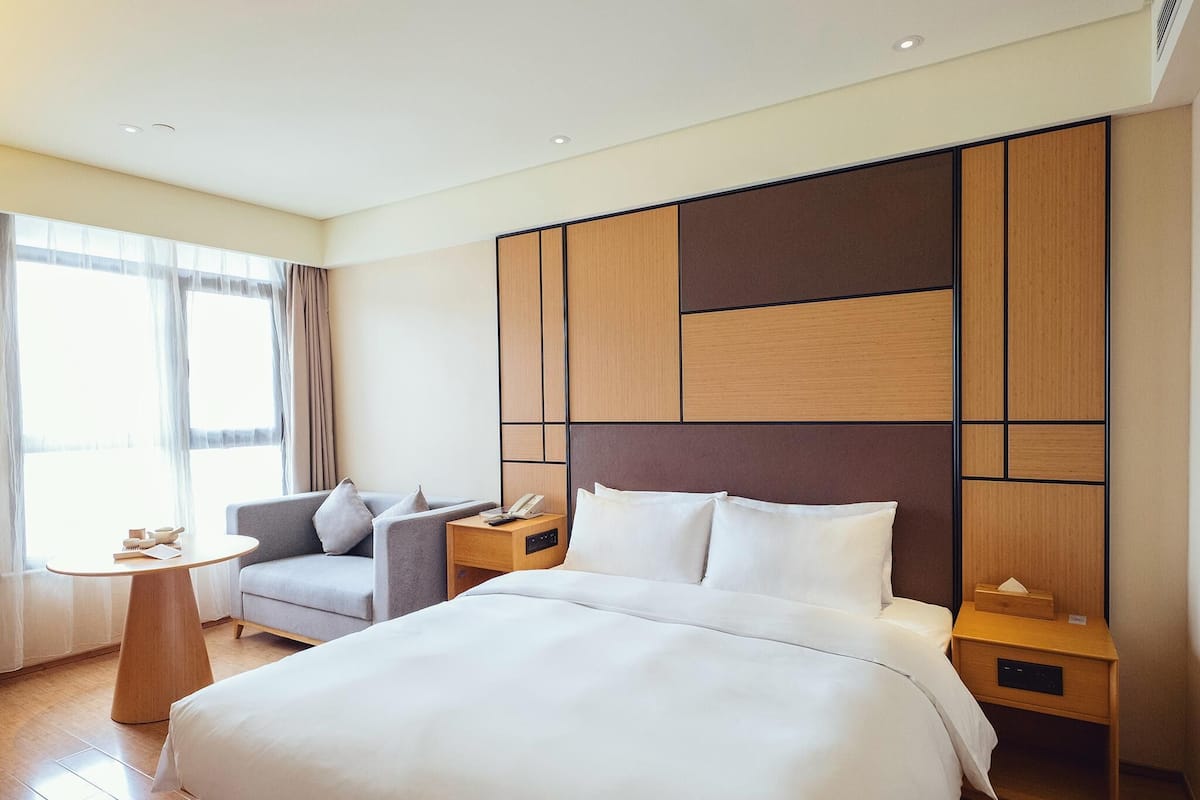 Une chambre d’hôtel avec un grand lit, un canapé, une petite table et une table de chevet avec un téléphone.