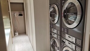 A laundry area with two front-loading washing machines and a dryer. - Ji Hotel (Shanghai)