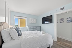 Een slaapkamer met een bed, een dressoir, een raam en kunst aan de muur.