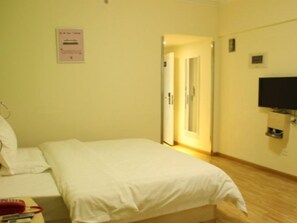 Habitació d'hotel amb un llit, una televisió penjada a la paret i una porta que dona a una altra habitació.